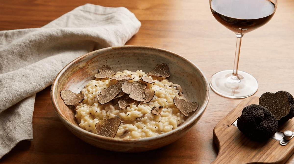 Risotto with wild porcini mushrooms and black truffles from Italy served in a plate close up on white table. Eating Italian gourmet cousine