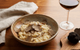 Risotto with wild porcini mushrooms and black truffles from Italy served in a plate close up on white table. Eating Italian gourmet cousine